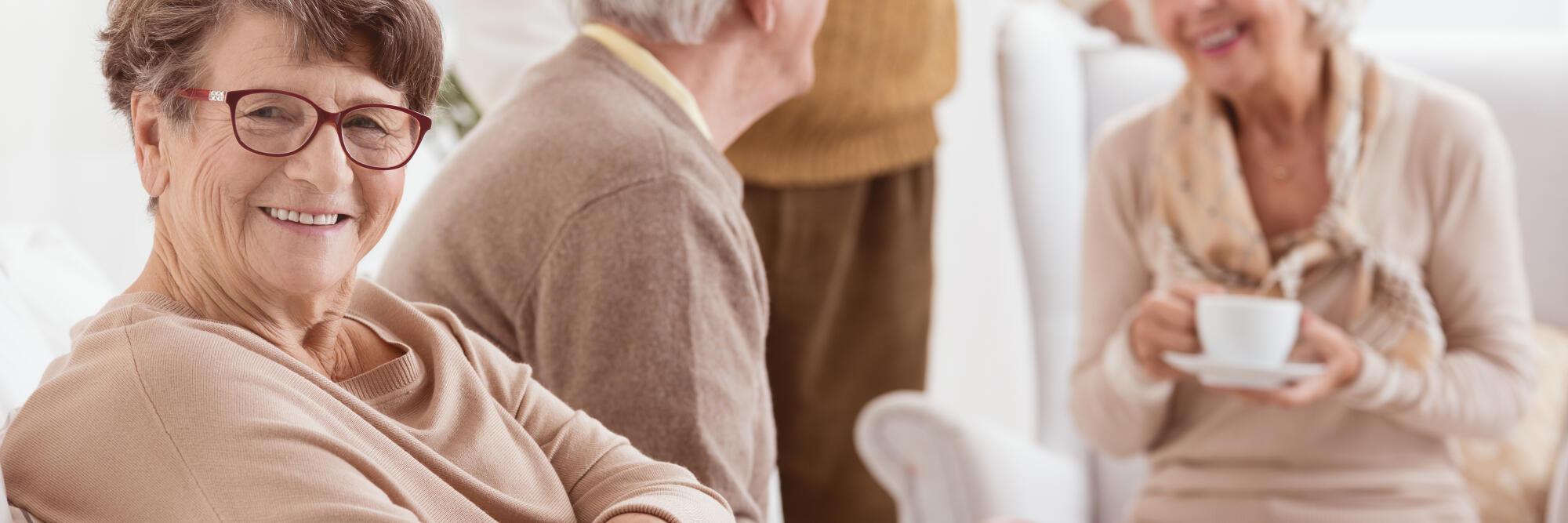 Smiling,Elderly,People,Sitting,In,A,Living,Room,And,Having